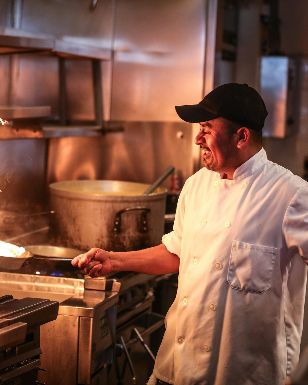 Cocinero sonriendo mientras saltea una sartén al fuego
