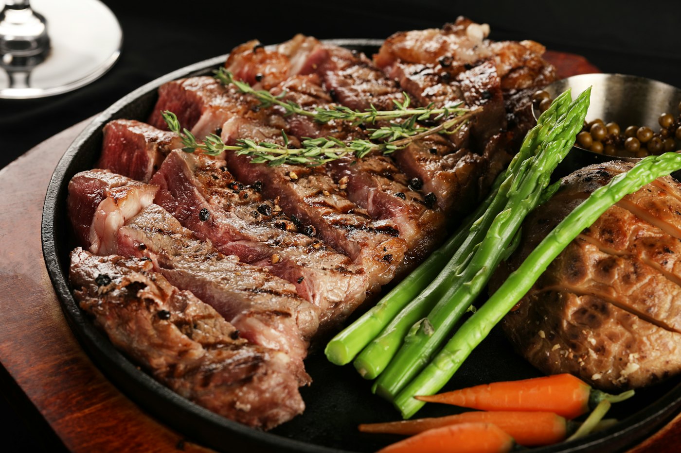 Lomo de vaca a la brasa cortado en lonchas, con tomillo, espárragos verdes y pimienta en grano